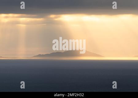 Golden rays of light shining through clouds on a heavenly evening looking towards the Outer Hebrides, seen from The Isle of Skye, Scotland, UK. Stock Photo