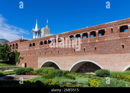 Red stone and brick bridge leading to Akhaltsikhe (Rabati) Castle, with cloisters and old moat overgrown with plants, flowers and grass. Stock Photo