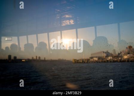 Silhouette of commuters reflecting on farry boat window during sunset Stock Photo