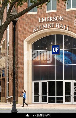 Female college student talking on a cell phone as she passes Emerson Alumni Hall on the University of Florida campus in Gainesville, Florida. (USA) Stock Photo