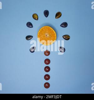 Orange Slice on Blue Background surrounded by gemstones. Flat Lay Composition. Summer fruit Stock Photo