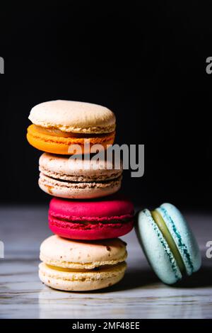 Macaron pink, orange and beige, blue on marble style and black background. French dessert on top of each other Stock Photo