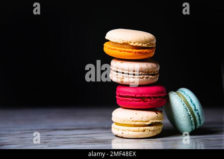Macaron pink, orange and beige, blue on marble style and black background. French dessert on top of each other Stock Photo