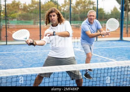 Focused man playing paddleball match on outdoor court Stock Photo
