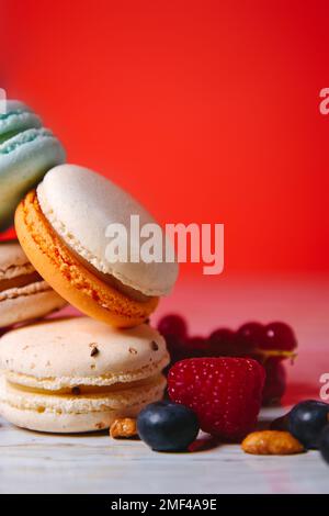 Colorful macarons. Small French cakes. Sweet and colorful french macaroons. Many tasty macarons with fresh berries, raspberries and blueberries, nuts Stock Photo