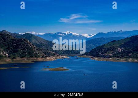 Lake Kaweah reservoir with a lone boat in the foreground and the snowy The Great Western Divide in the background Stock Photo