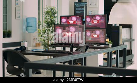 Empty agency office with multiple monitors showing system crash warning on display, critical error message flashing on screen. Computers displaying security breach malfunction at desk. Stock Photo