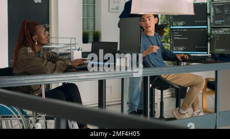 African american developer with disability working with programming language on terminal window. IT engineer in wheelchair using html script to develop new program interface on computer. Stock Photo