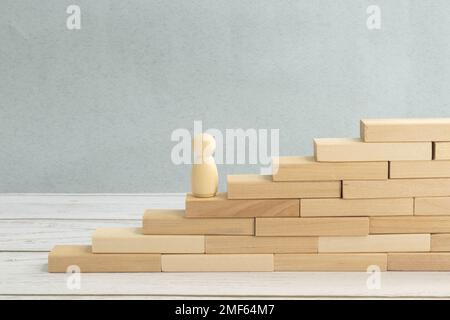 A red man stands at the top of a social or career ladder. Concept of business success. Stairs of people. Use other workers. A wooden figure of a man a Stock Photo