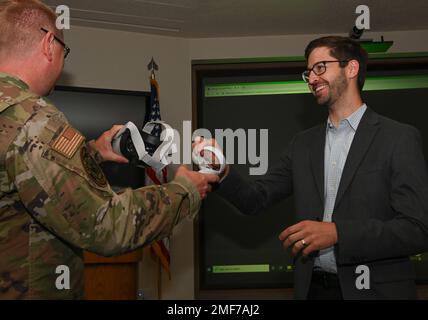 Lt. Col. Larry Rochat United States Global Strike Command, hands a virtual reality headset to Adam Wilkerson, civilian civil engineer, at Whiteman Air Force Base, Missouri, August 17, 2022. The headsets dispalyed 3D images of the upcoming flightline changes to accommodate the B-21 Raider. AIR FORCE,B-2 Spirit,B-21 Raider,Bomb Wing,Virtual Reality,aircraft, Stock Photo