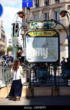 A passenger looking at the metro map on an historic Art Nouveau metro entrance of Louvre-Rivoli metro station.Paris,France Stock Photo