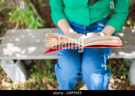 Unrecognizable student woman reading a book in the backyard. World Book Day. Benefits of reading Stock Photo