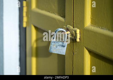 Yellow wood door closed with rusty padlock. Security concept. Stock Photo