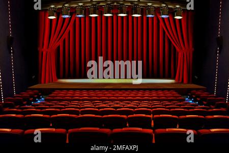 theater stage with red curtains and seats under spotlights Stock Photo