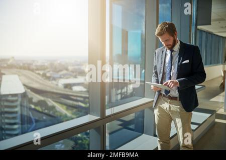 Its the way he works. a handsome young businessman using a tablet in his office. Stock Photo