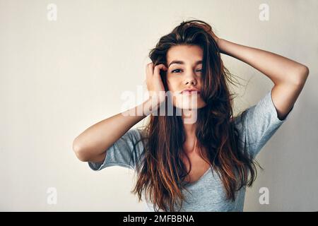 Play with my hair and well have a deal. Studio shot of an attractive young woman posing with her hands in her hair. Stock Photo