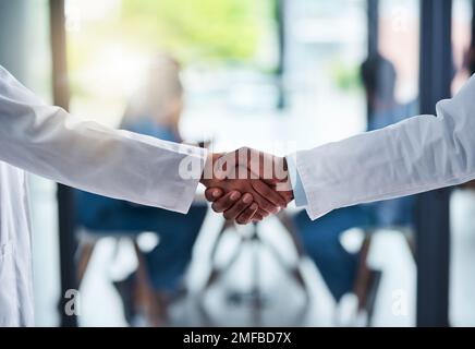 Doctors you can trust. two unrecognizable doctors shaking hands inside of a hospital during the day. Stock Photo