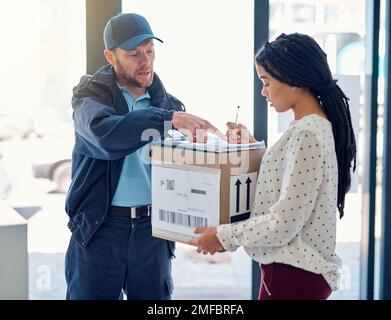 I just need your signature right there...a handsome delivery man getting a signature from a female customer for her order. Stock Photo