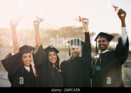 Holding up the key to their successful future. Portrait of a group of students celebrating with their diplomas on graduation day. Stock Photo