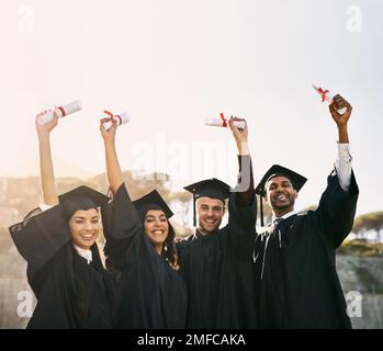 Watch us succeed and excel even more from here on. Portrait of a group of students celebrating with their diplomas on graduation day. Stock Photo