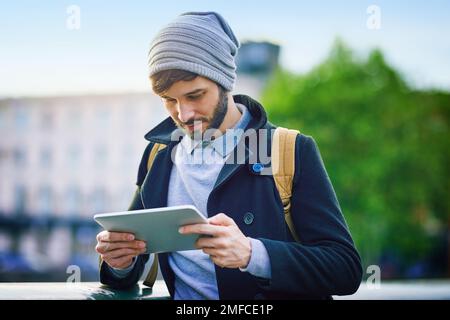 Navigating the city with smart tech. a young man using a digital tablet while out in the city. Stock Photo