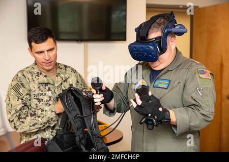 Lt. Cmdr. Ben O'neill, right, assigned to the Naval Education and Training Command's (NETC) Command at Sea Training Department office, participates in a virtual reality diver simulation at NETC headquarters in Pensacola, Florida, August 19, 2022. Leaders from Naval Diving and Salvage Training Center, including Chief Warrant Officer James Dertilis, left, visited NETC as part of an extended reality (XR) training device discussion with NETC leadership. Ready Relevant Learning is delivering modernized content in support of transformational changes to the when, how and where the Navy trains Sailors Stock Photo