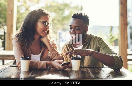 Id love to see more pictures of your cat. a young couple using a mobile phone together at a cafe. Stock Photo