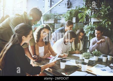 Who said business has to be in a boardroom. a group of colleagues having a meeting at a cafe. Stock Photo