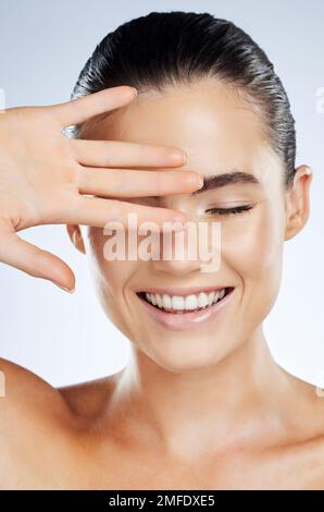 Face, beauty and skincare of a woman in studio with a smile for natural cosmetic product. Happy aesthetic model person show hand for makeup, facial Stock Photo