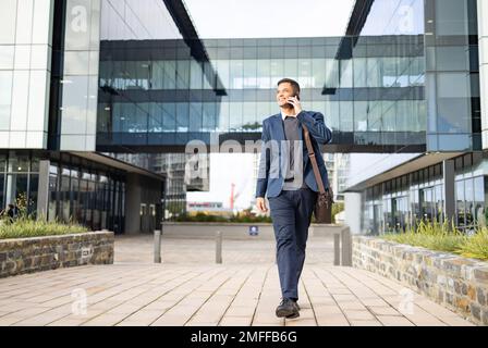 Phone call, communication and happy businessman walking, networking and talking on 5g conversation in New York. Architecture mockup, real estate agent Stock Photo
