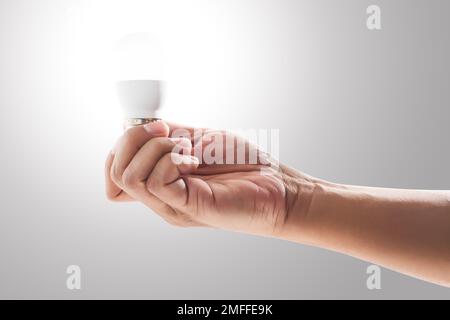 Light bulb on human hand with gray background. Stock Photo