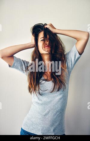 My hair is my art. Studio shot of an attractive young woman posing with her hands in her hair. Stock Photo