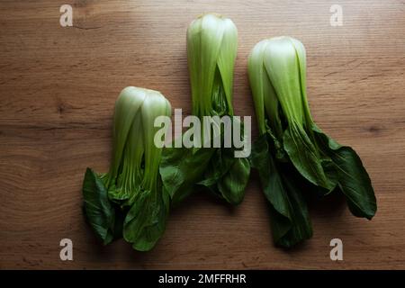 Three bok choy on a wooden kitchen table, top view Stock Photo