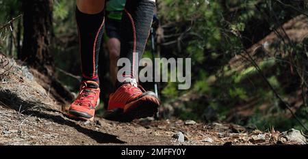 Trail running workout outdoors on rocky terrain, sports shoes detail on a challenging forest track Stock Photo