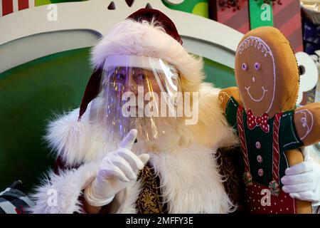 Santa Claus wears a face mask covering while waiting for children