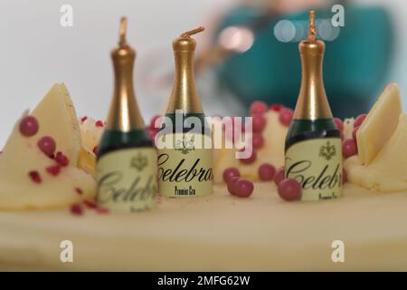 Champagne shaped birthday candles sitting on top of a Birthday Cake, with the letters celebrate around them. a trio of candles Stock Photo