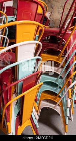 stack of multicolored chairs of Industrial Metal Chair on restaurant terrace Stock Photo