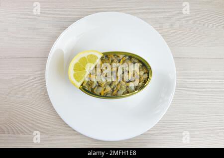 Can of cockles on a plate on rustic wooden table Stock Photo