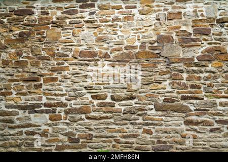 Old stone wall of a building. Stone wall as background or rustic pattern for wallpaper. Stock Photo