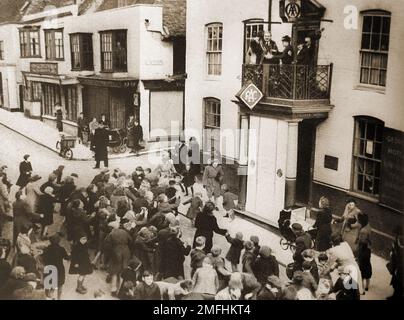 British pubs inns & taverns - A circa 1940 old photograph of  the George at Rye with the mayor taking part in the annual ceremony of throwing  of hot pennies  from the balcony to the children below. Stock Photo