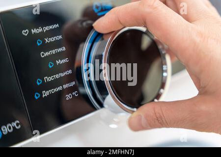 woman's hand selects the washing mode with a round selector Stock Photo