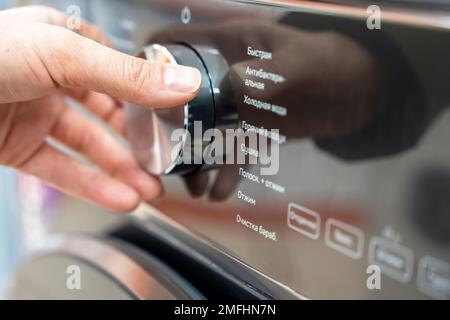 woman's hand selects the washing mode with a round selector Stock Photo