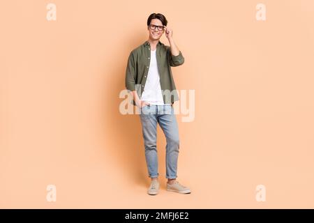 Full body length size cadre of young optimistic man wear stylish outfit casual style new eyeglasses advertisement isolated on beige color background Stock Photo