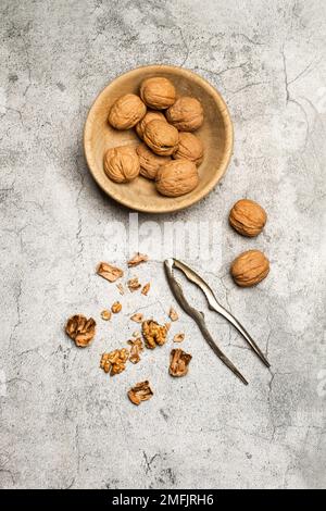 Walnuts in a wooden bowl and a nutcracker on a marble kitchen countertop Stock Photo