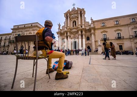 A musician plays the accordion in the square Piazza Duomo in front of the Cathedral of Syracuse, Duomo di Siracusa in the Late Baroque town. Stock Photo