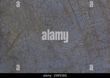 The old metal surface is covered with cracked gray paint with rust spots. Stock Photo