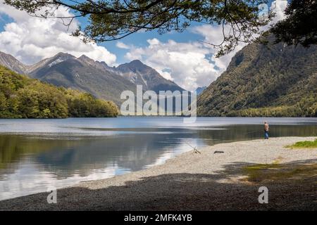 Lake Gunn, South Island, New Zealand - 17th December 2022: A man fishes with rod and line in the calm waters of Lake Gunn in the South Island of New Z Stock Photo