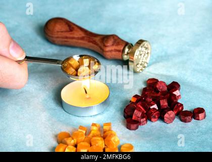 hand holding a candle wax  melting spoon and seal  a traditional  using hot wax and a seal stamp to create a unique, personalized seal on the document Stock Photo
