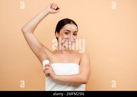 Portrait Of Smiling Young Indian Woman Using Antiperspirant Stick For Underarms Stock Photo