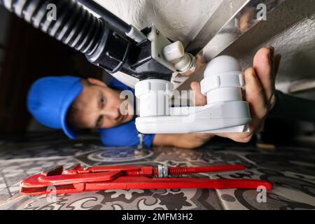 plumbing service. plumber at work in bathroom. repair and install drain siphon under the bath Stock Photo